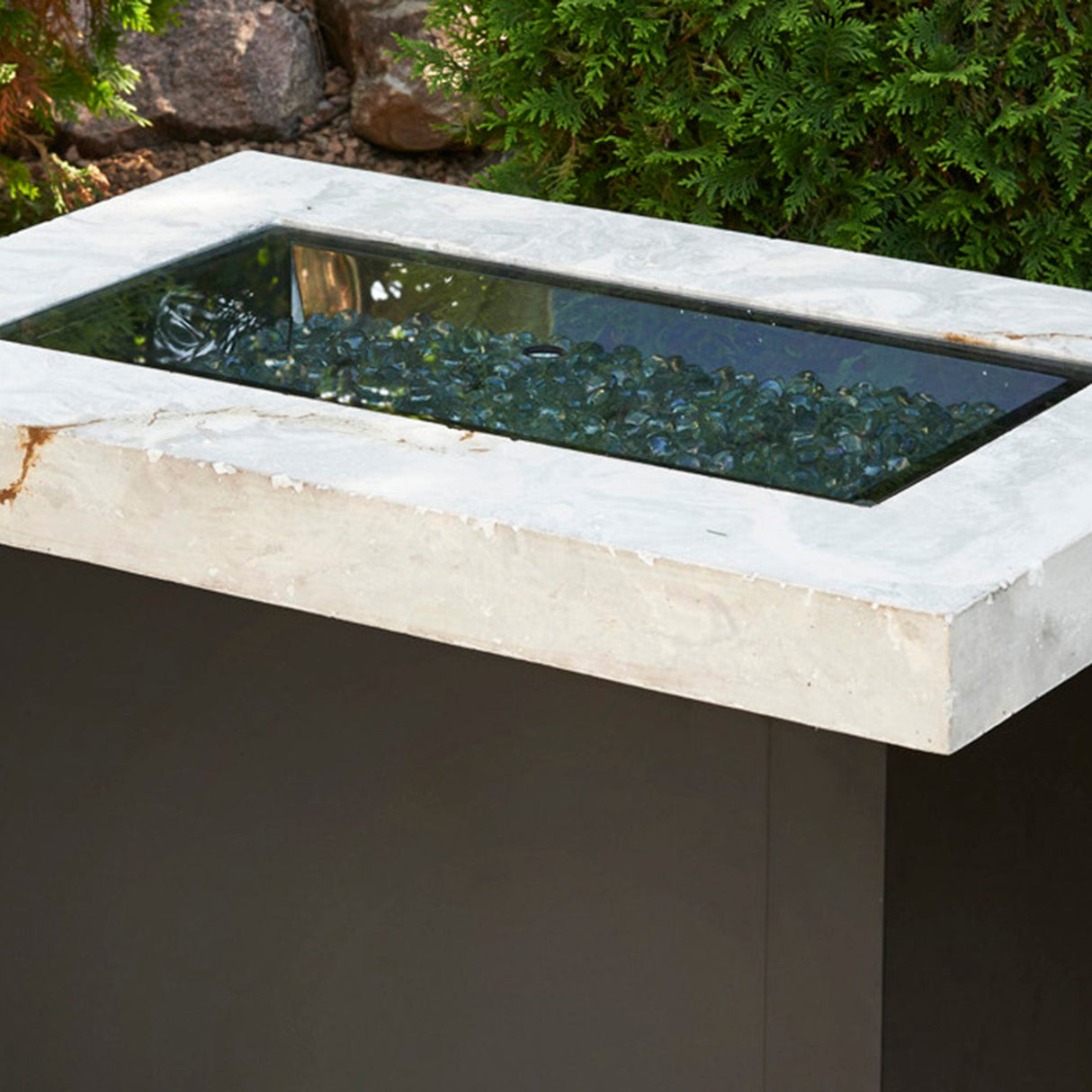 The Linear Glass Burner Cover covering a fire pit table on a patio