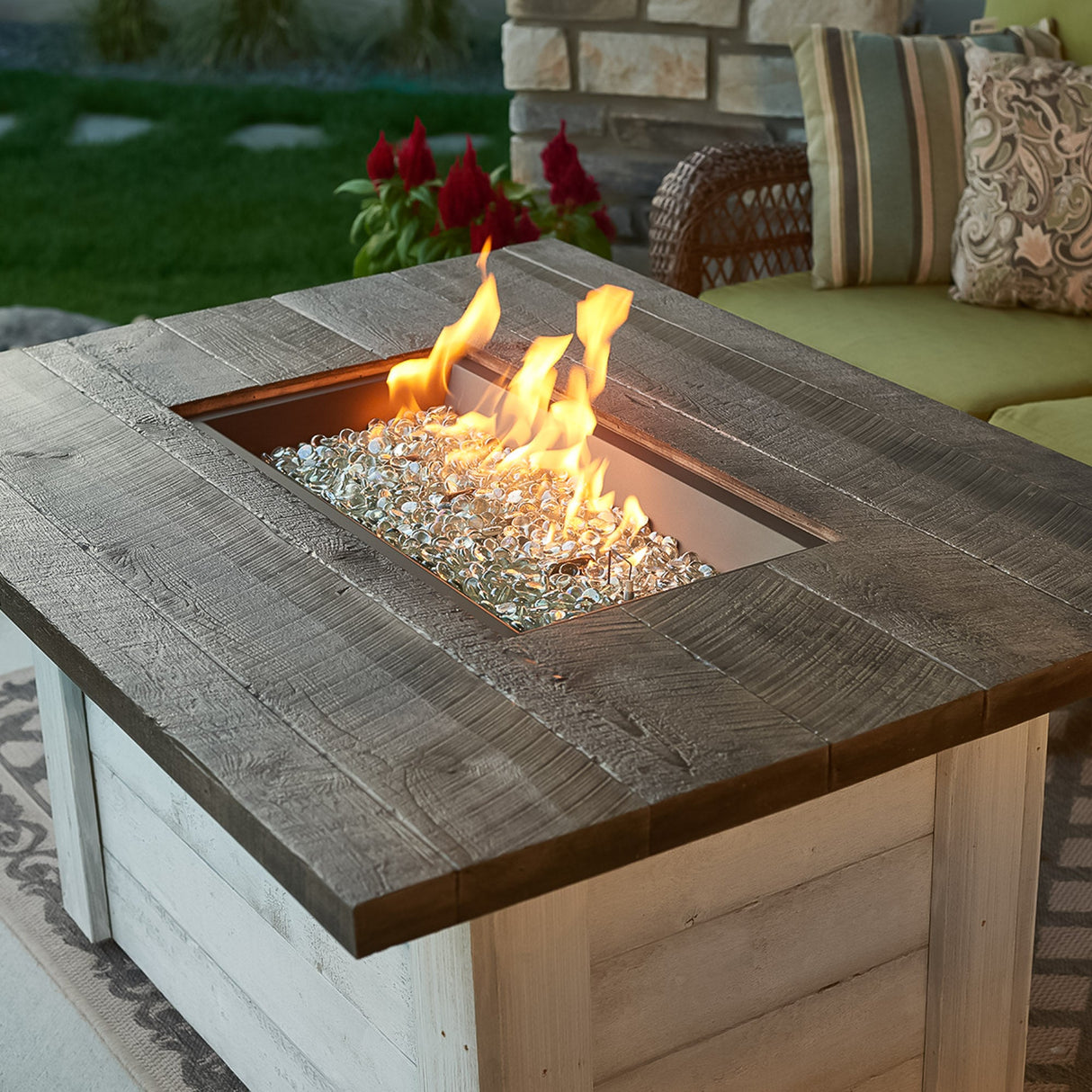 A Alcott Rectangular Gas Fire Pit Table placed in an outdoor space with a large flame