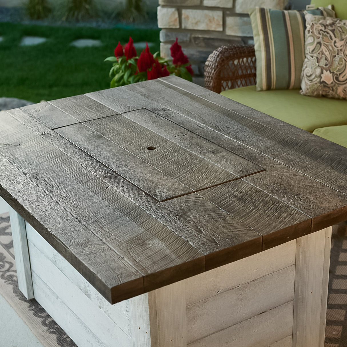 A cover placed on the Alcott Rectangular Gas Fire Pit Table while surrounded next to patio furniture