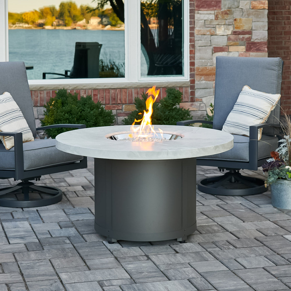 The White Onyx Beacon Round Gas Fire Pit Table outside in a patio setting