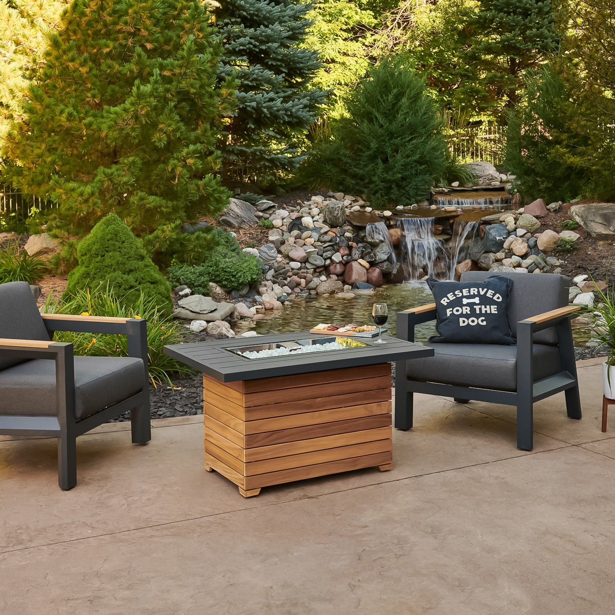 The Darien Rectangular Gas Fire Pit Table with an Aluminum top in an outdoor setting surrounded by patio furniture