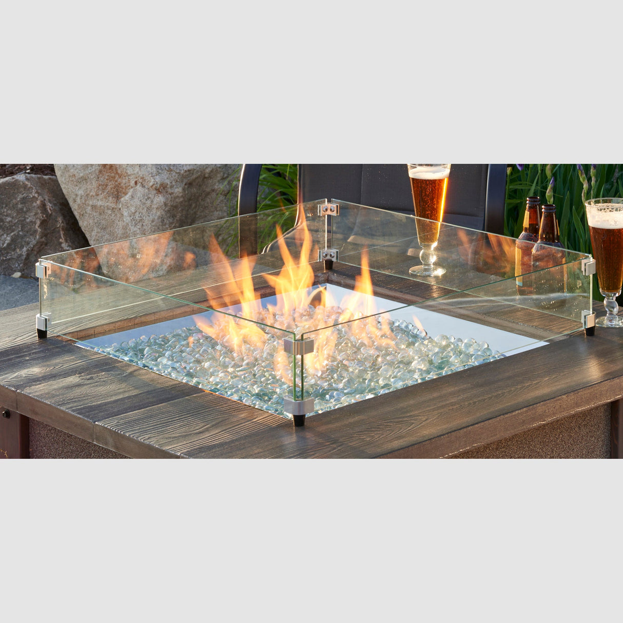 The Square Glass Wind Guard being used on a patio setting with drinks on the fire pit table