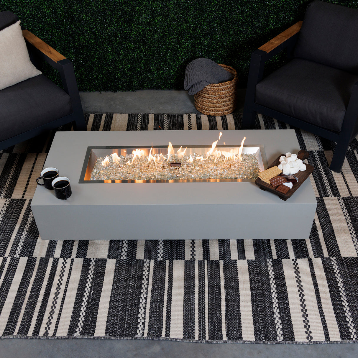 A top view of the Harbor View Rectangular Gas Fire Pit Table with food and drink on the sides around the fire