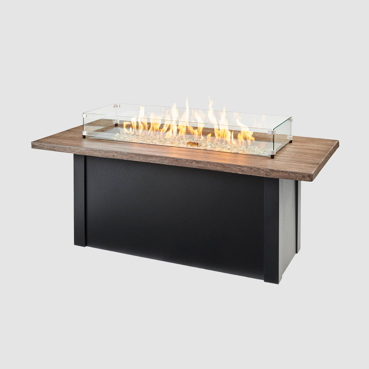 A glass wind guard placed on top of a Havenwood Linear Gas Fire Pit Table with a Driftwood top and Luverne Black base on a grey background