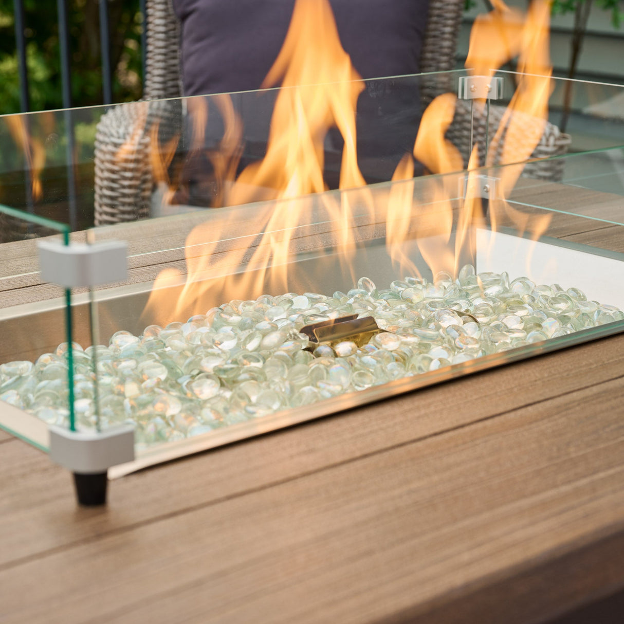 A close up of the flame from the burner of a Havenwood Rectangular Gas Fire Pit Table with a Driftwood top