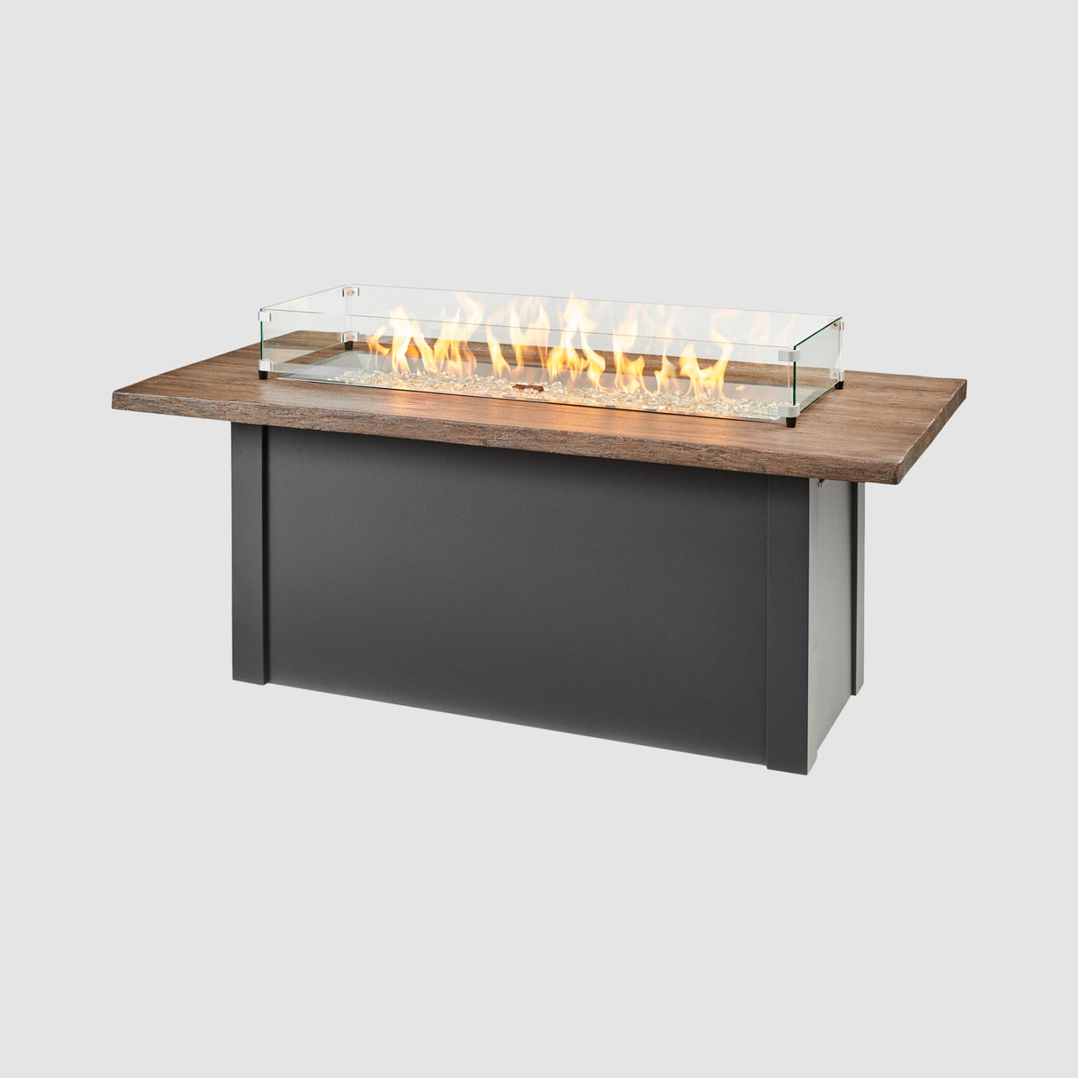 A glass wind guard placed on top of a Havenwood Linear Gas Fire Pit Table with a Driftwood top and Graphite Grey base
