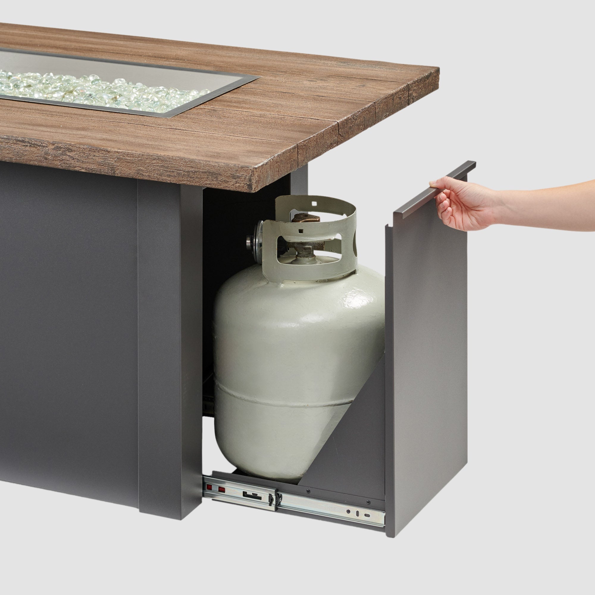 The side access door being opened on a Havenwood Linear Gas Fire Pit Table with a Driftwood top and Graphite Grey base