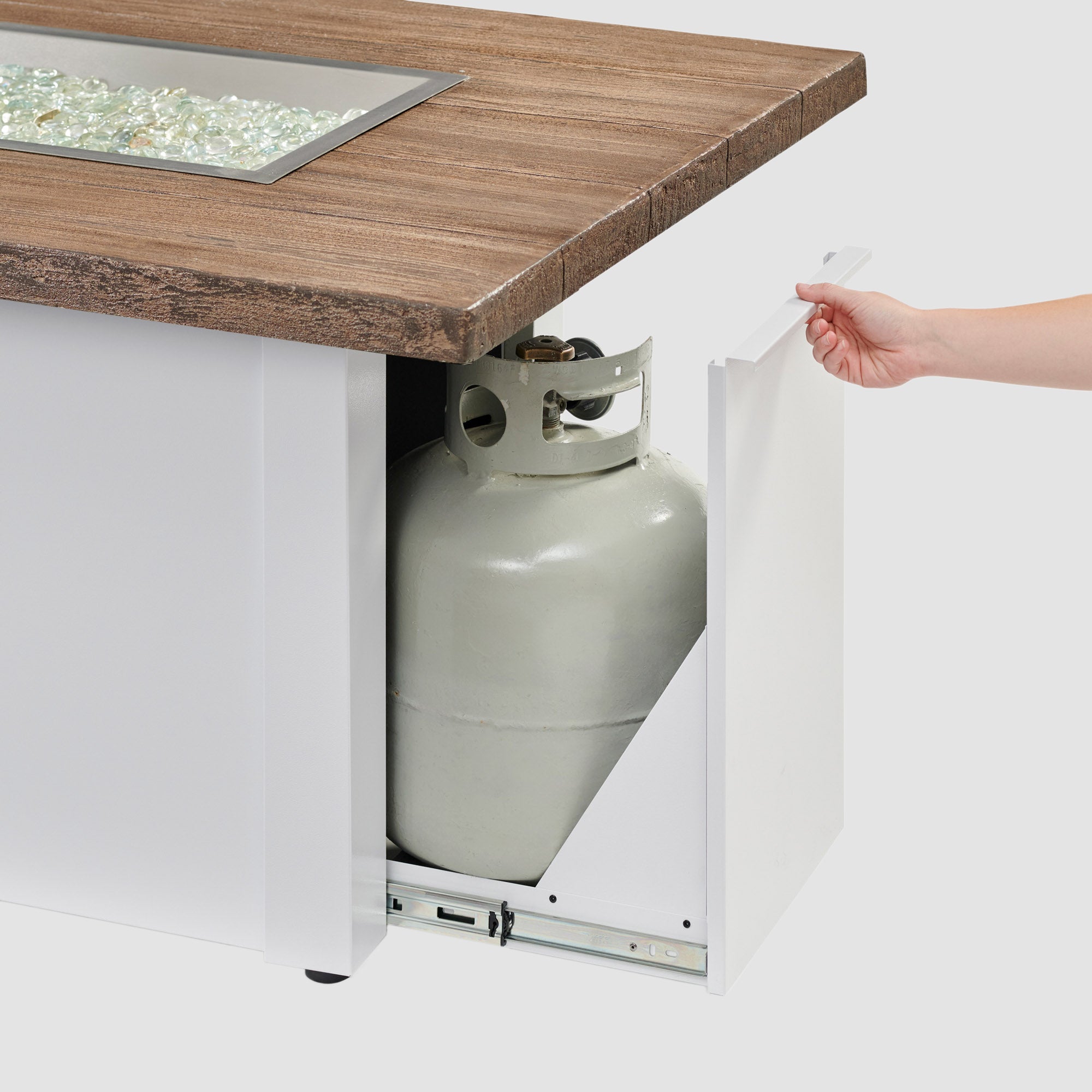 The side access door being opened on a Havenwood Linear Gas Fire Pit Table with a Driftwood top and White base