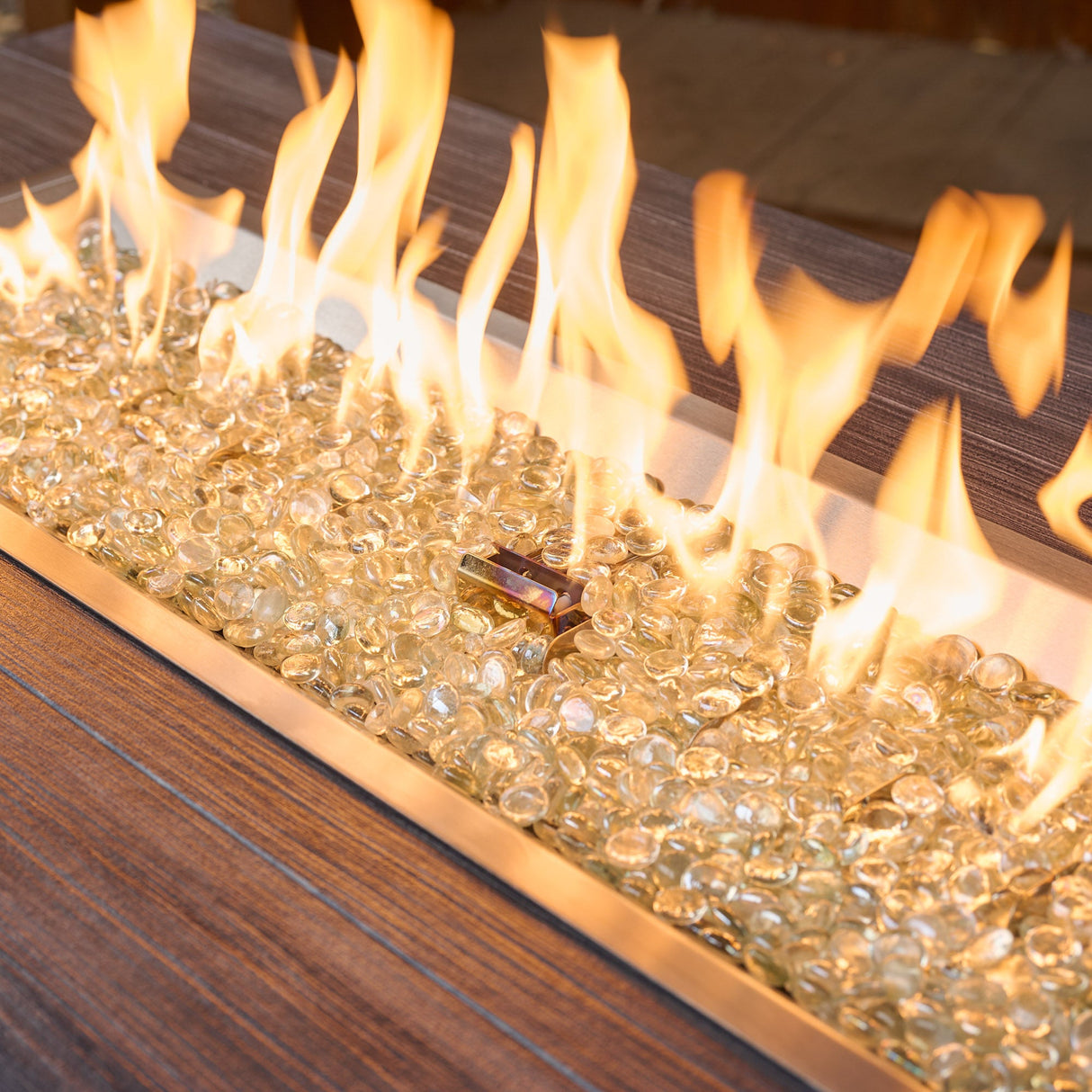 A close up of the flame coming from the Havenwood Linear Gas Fire Pit Table with a Carbon Grey top and Luverne Black base