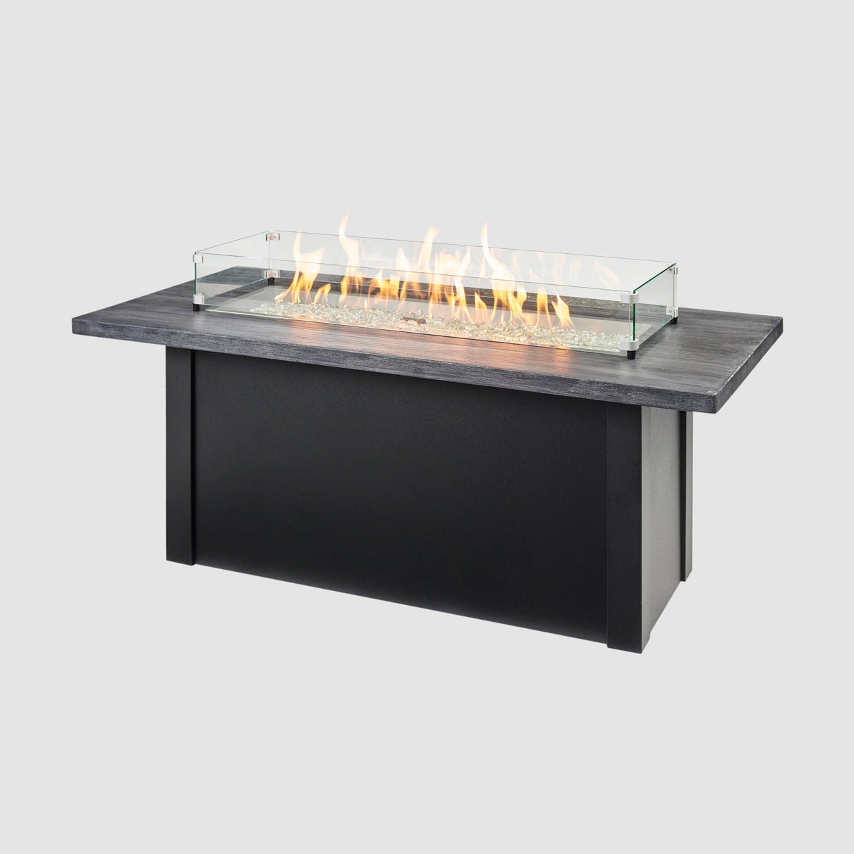 A glass wind guard placed on top of a Havenwood Linear Gas Fire Pit Table with a Carbon Grey top and Luverne Black base