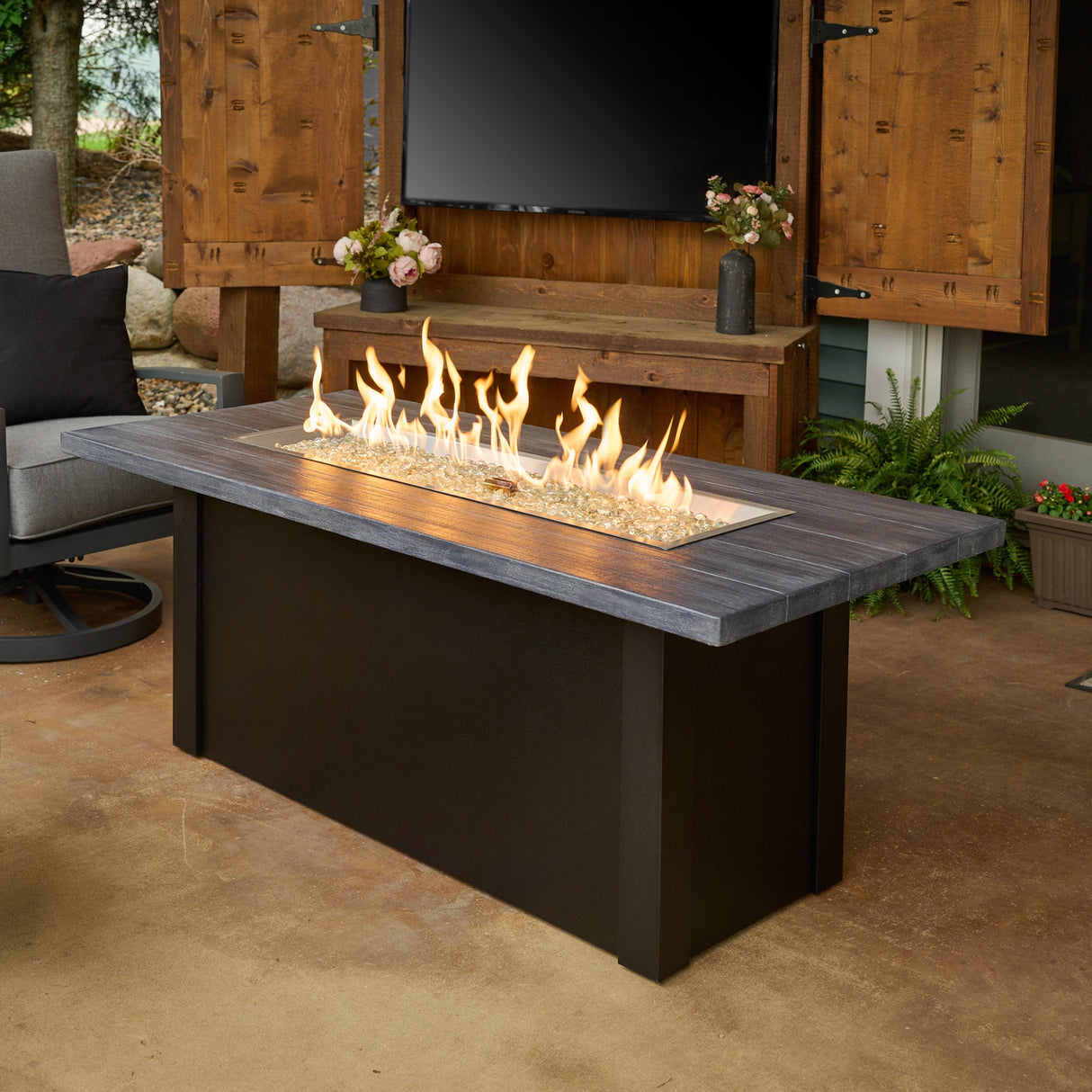 The Havenwood Linear Gas Fire Pit Table with a Carbon Grey top and Luverne Black base in a scenic outdoor patio