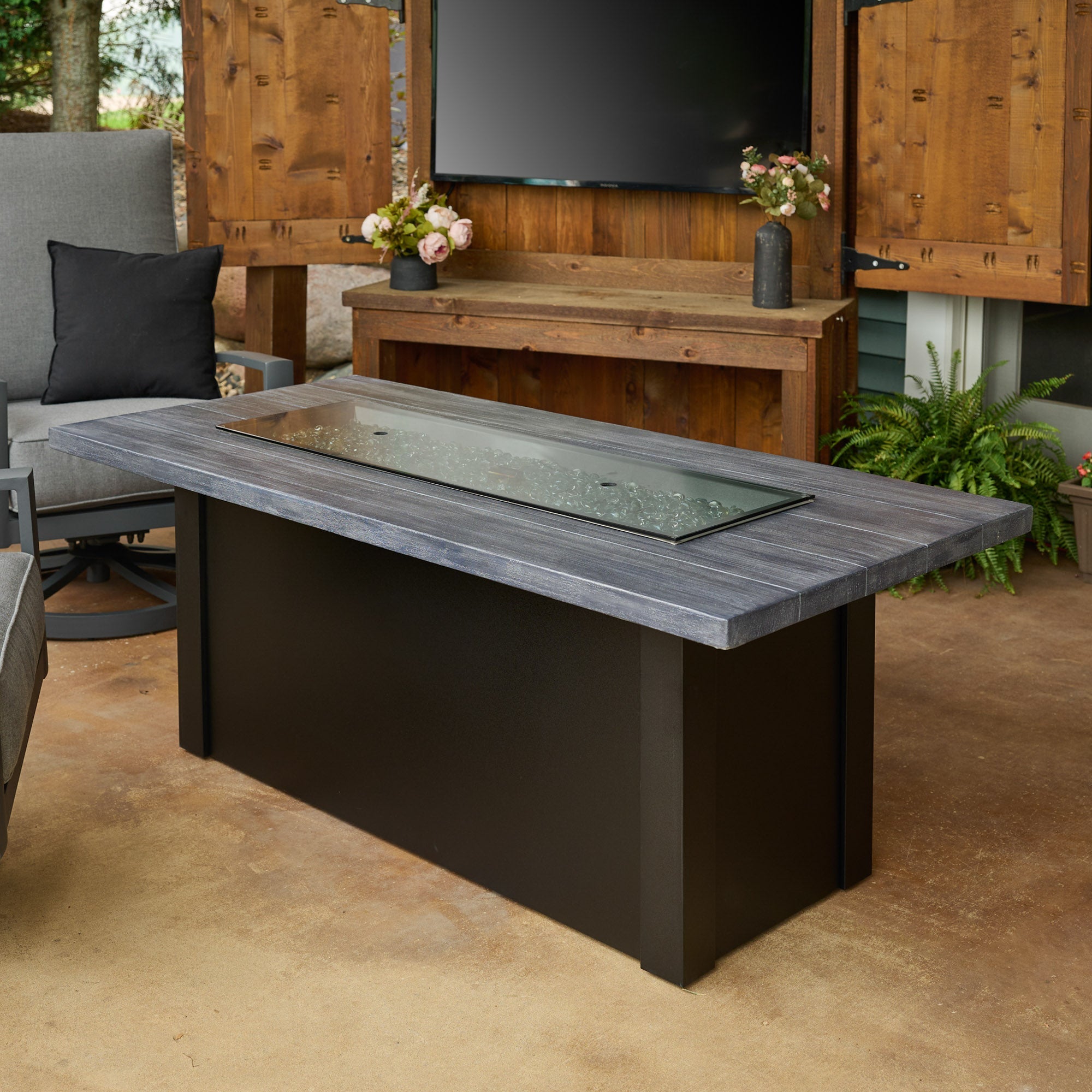 The Havenwood Linear Gas Fire Pit Table with a Carbon Grey top and Luverne Black base being used as a table with its cover placed on the burner