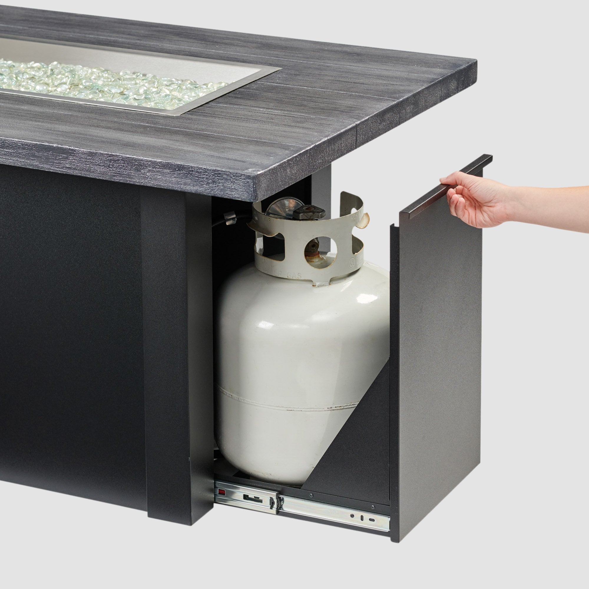 The side access door being opened on a Havenwood Linear Gas Fire Pit Table with a Carbon Grey top and Luverne Black base