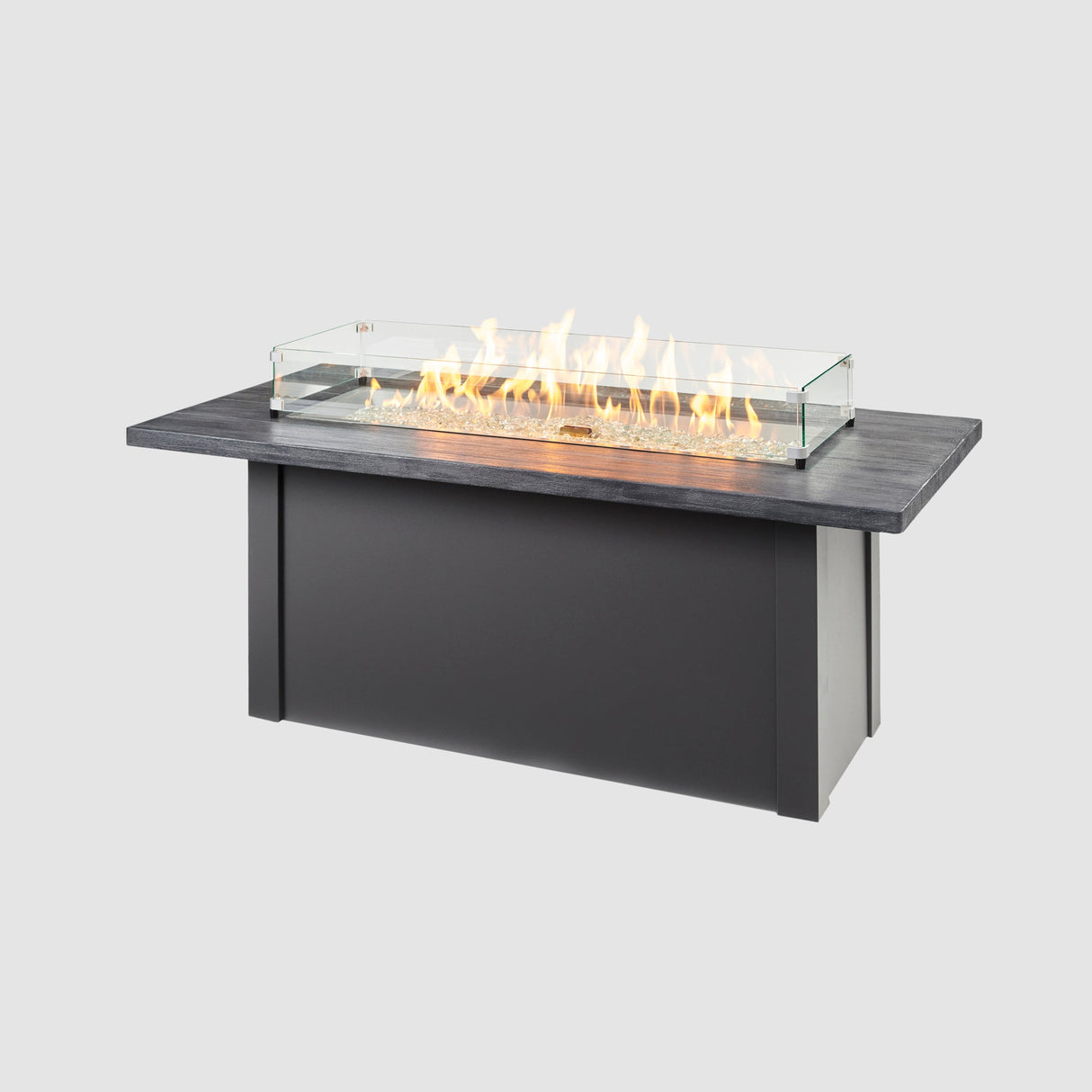 A glass wind guard placed on the top of a Havenwood Linear Gas Fire Pit Table with a Carbon Grey top and Graphite Grey base