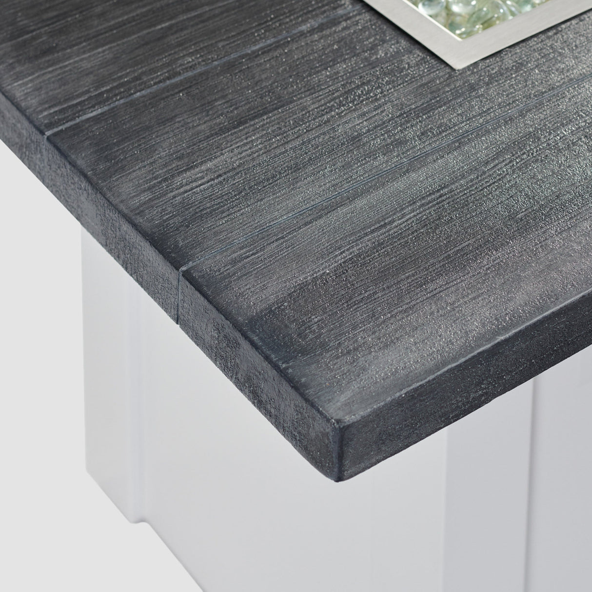 A close up view of the detail found on the top of a Havenwood Linear Gas Fire Pit Table with a Carbon Grey top and White base