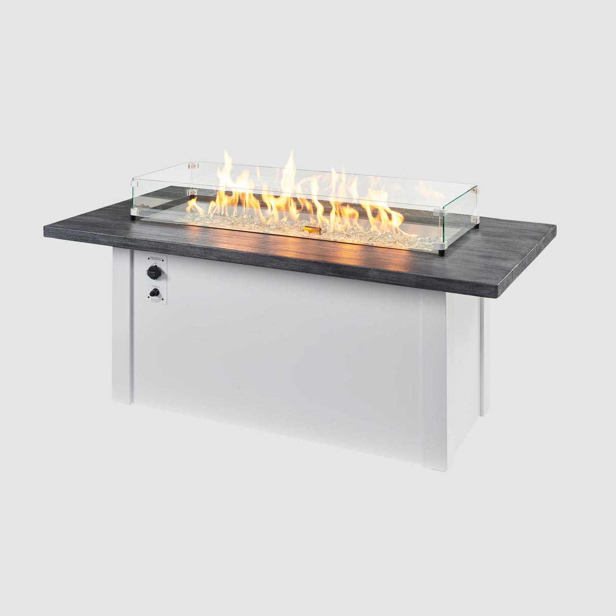 A glass wind guard placed on the top of a Havenwood Linear Gas Fire Pit Table with a Carbon Grey top and White base