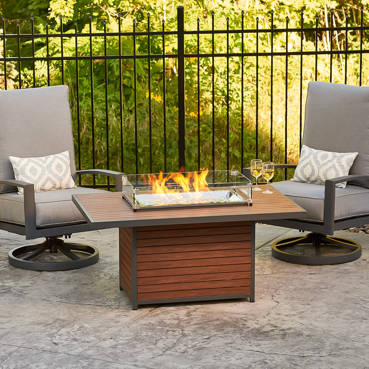 The Kenwood Rectangular Chat Height Gas Fire Pit Table in an outdoor space with lounge chairs
