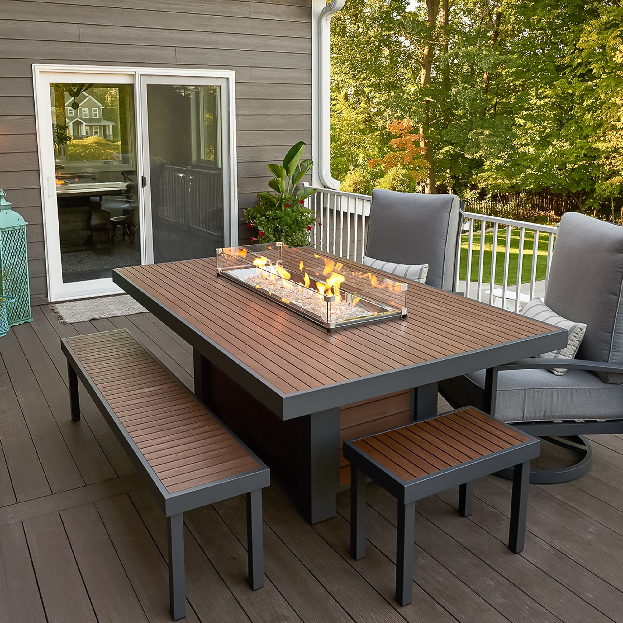 A glass wind guard placed on the top of the Kenwood Linear Dining Height Gas Fire Pit Table while outside