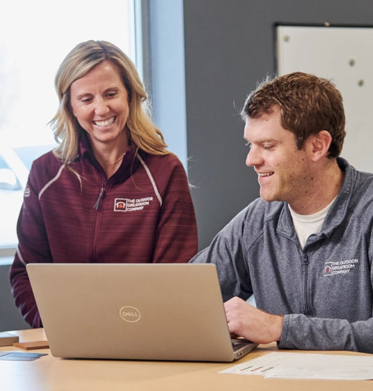 Two Outdoor GreatRoom Company employees gathered next to a laptop