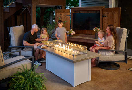 A family roasts marshmallows around a Havenwood linear gas fire pit table