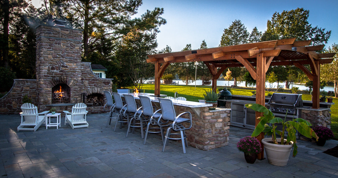 A custom outdoor island with a pergola, outdoor fireplace, and assorted patio furniture