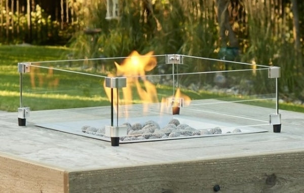 A 16" x 16" square glass wind guard protecting the flame of a square gas fire pit table