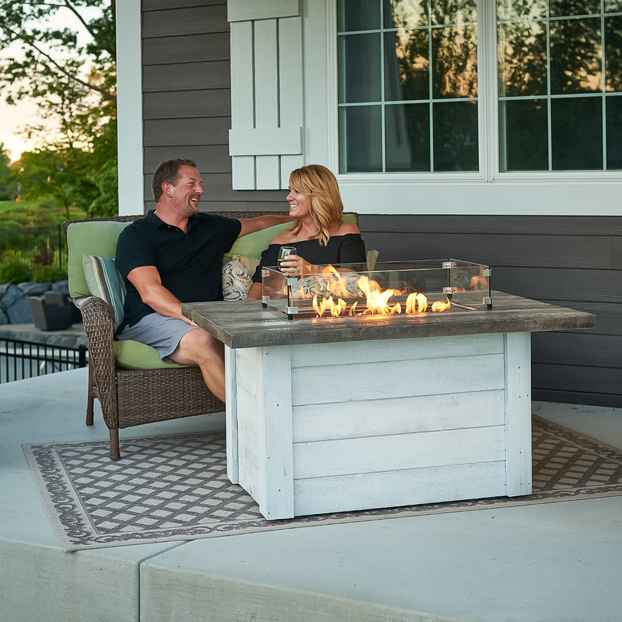 Two individuals conversing next to the Alcott Rectangular Gas Fire Pit Table