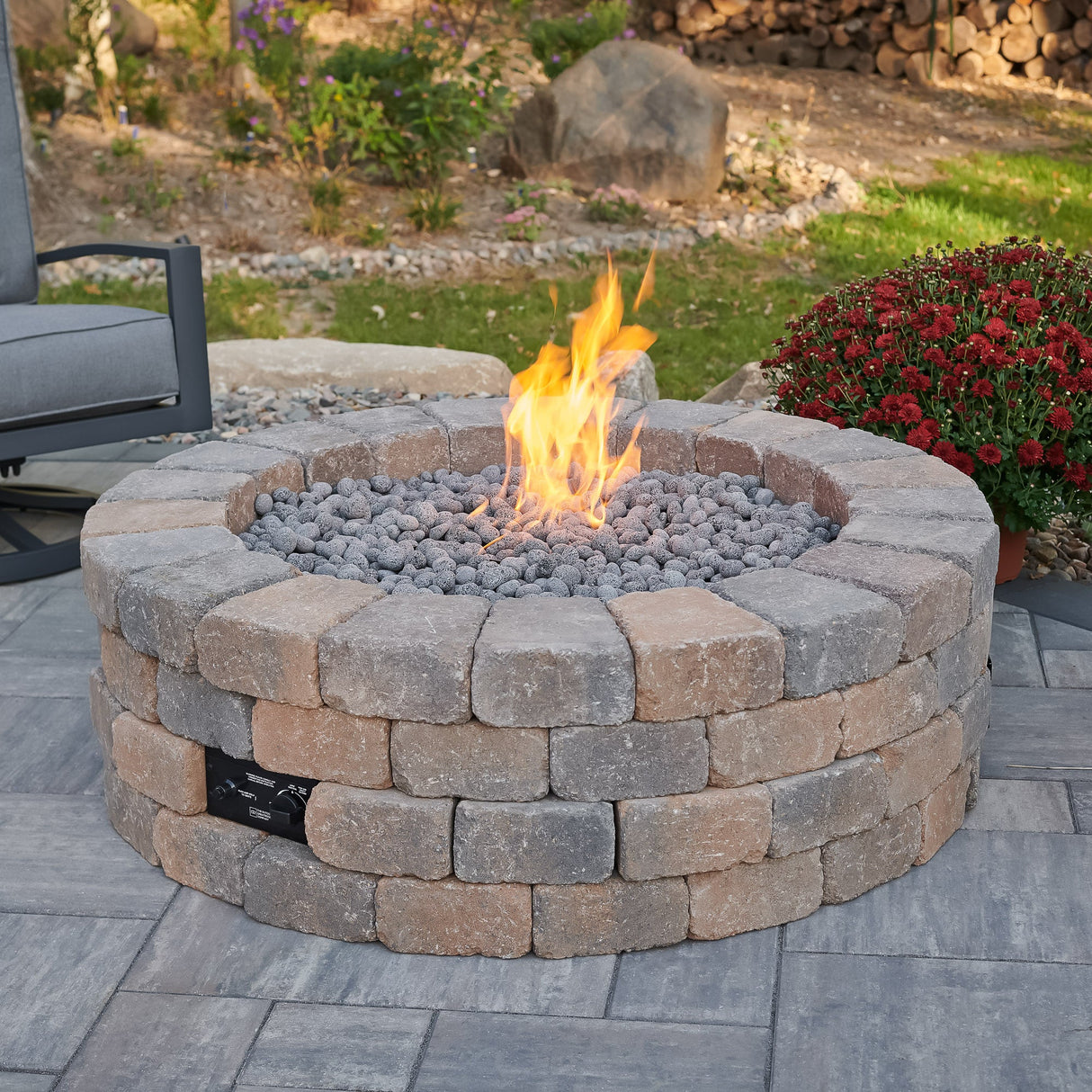 The Bronson Block Round Gas Fire Pit Kit in an outdoor setting with a large flame