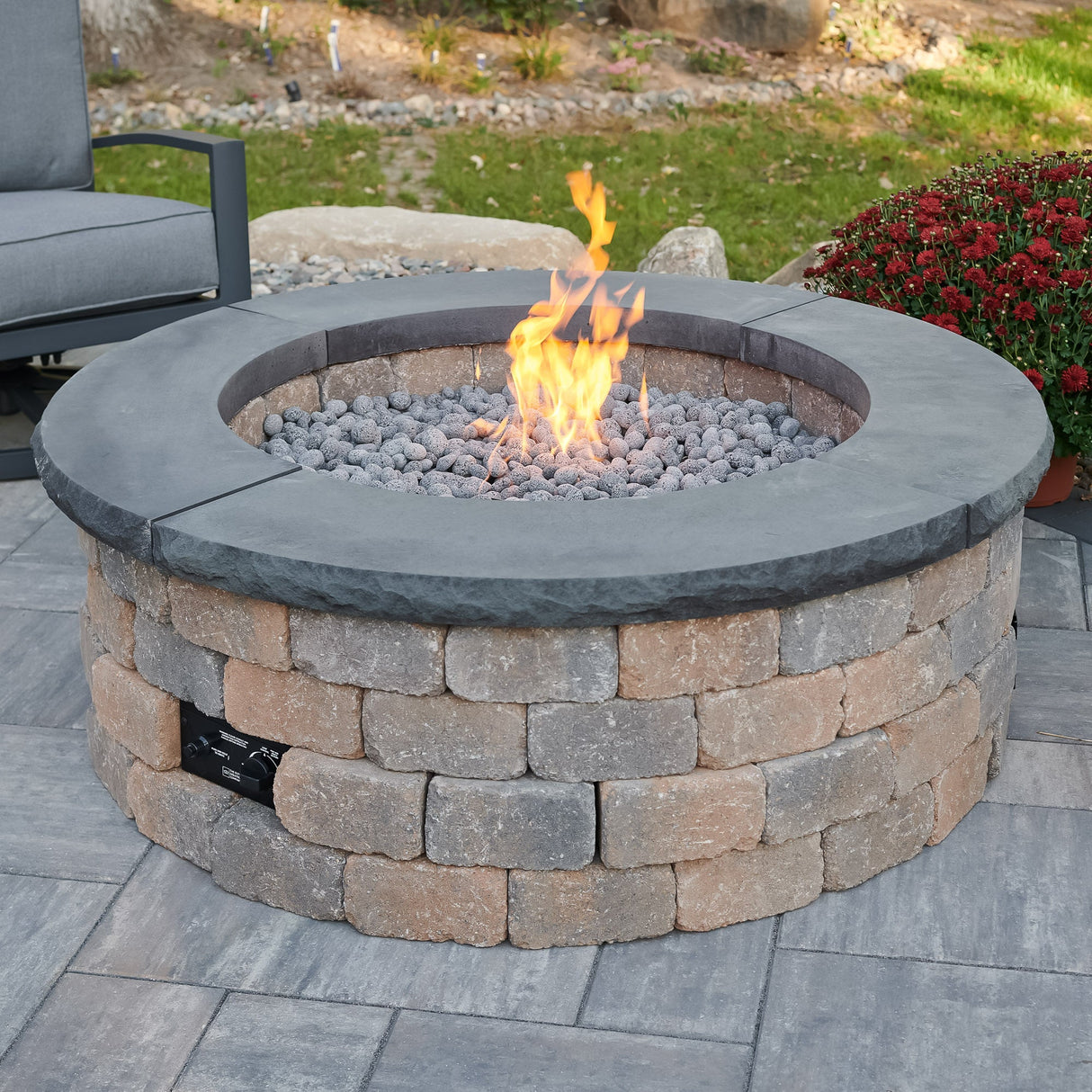 Charcoal Grey Concrete Top for Round Bronson Block Gas Fire Pit Kit with flame on a patio