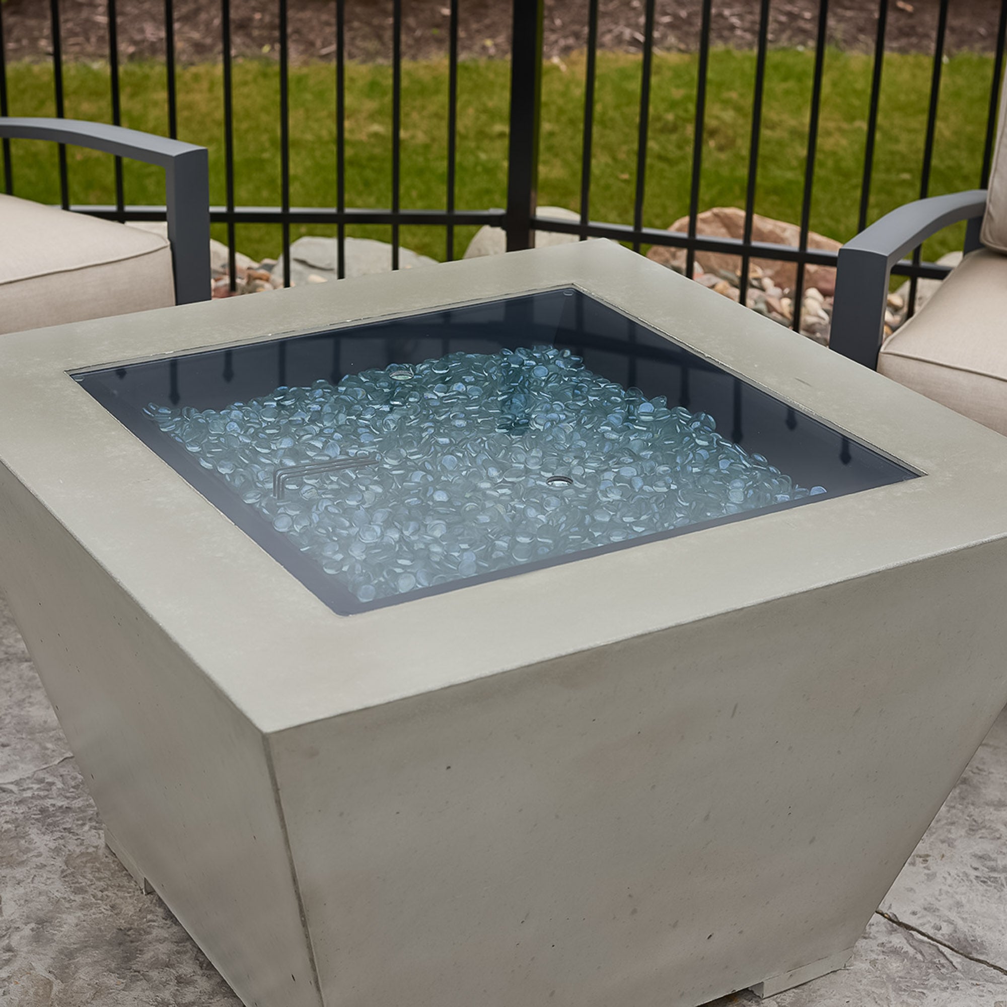 A close up view of the Cove Square Gas Fire Pit Bowl, its cover, and the fire media placed on the burner