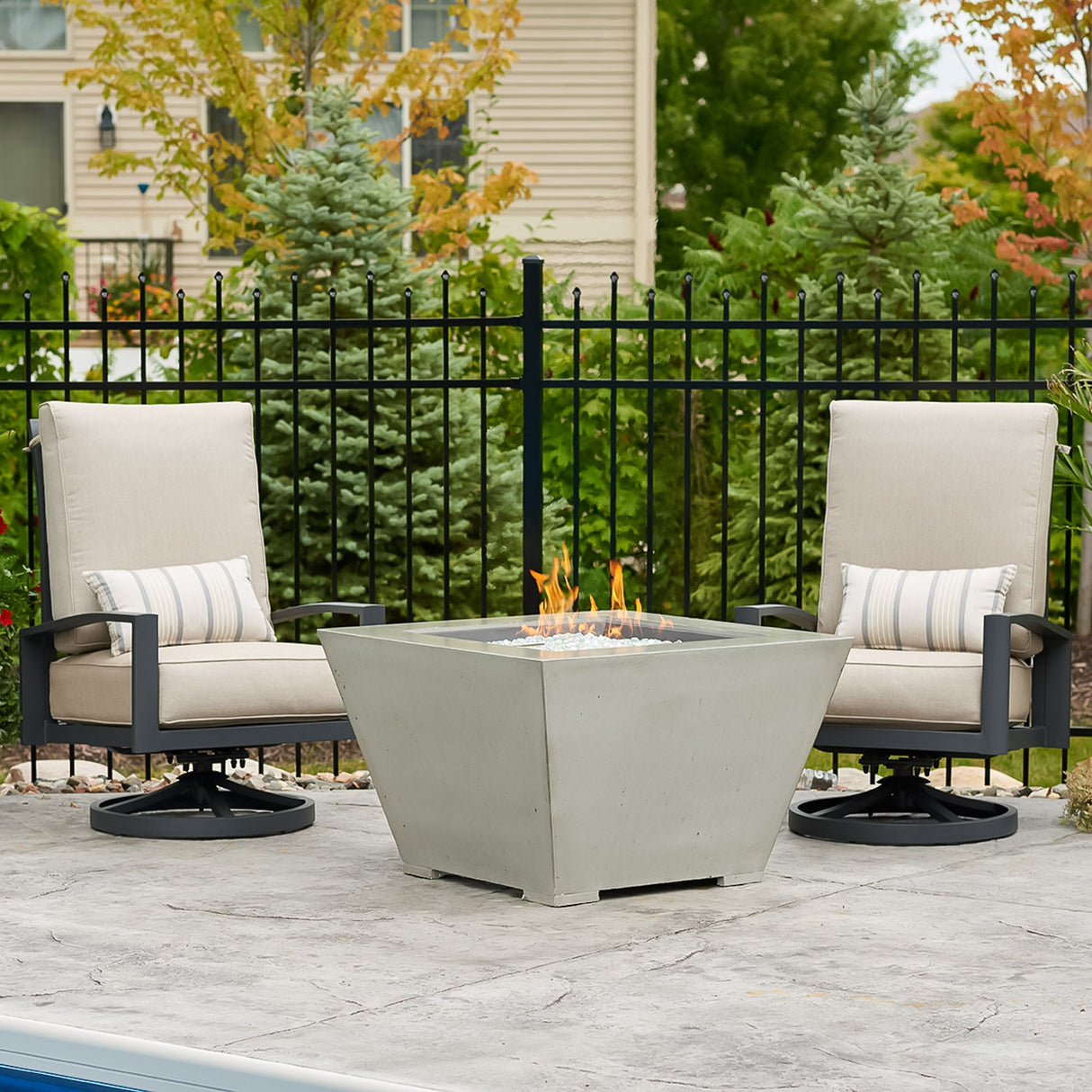 The Cove Square Gas Fire Pit Bowl standing next to patio furniture in an outdoor space