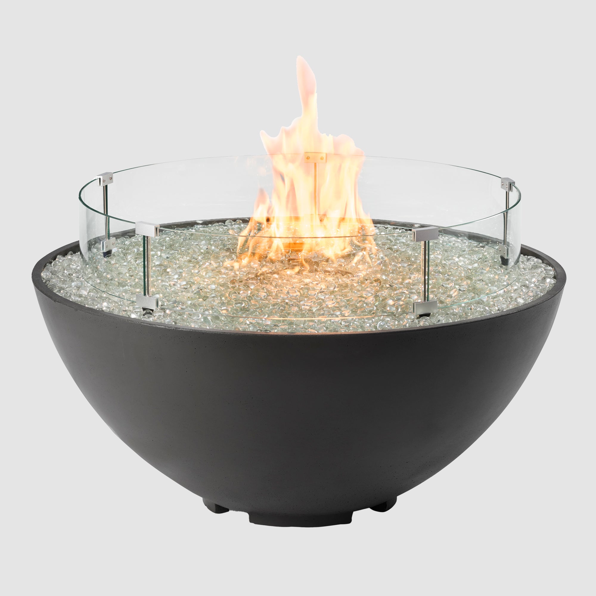 A glass wind guard placed on a Midnight Mist Cove Edge Round Gas Fire Pit Bowl 42" on a grey background