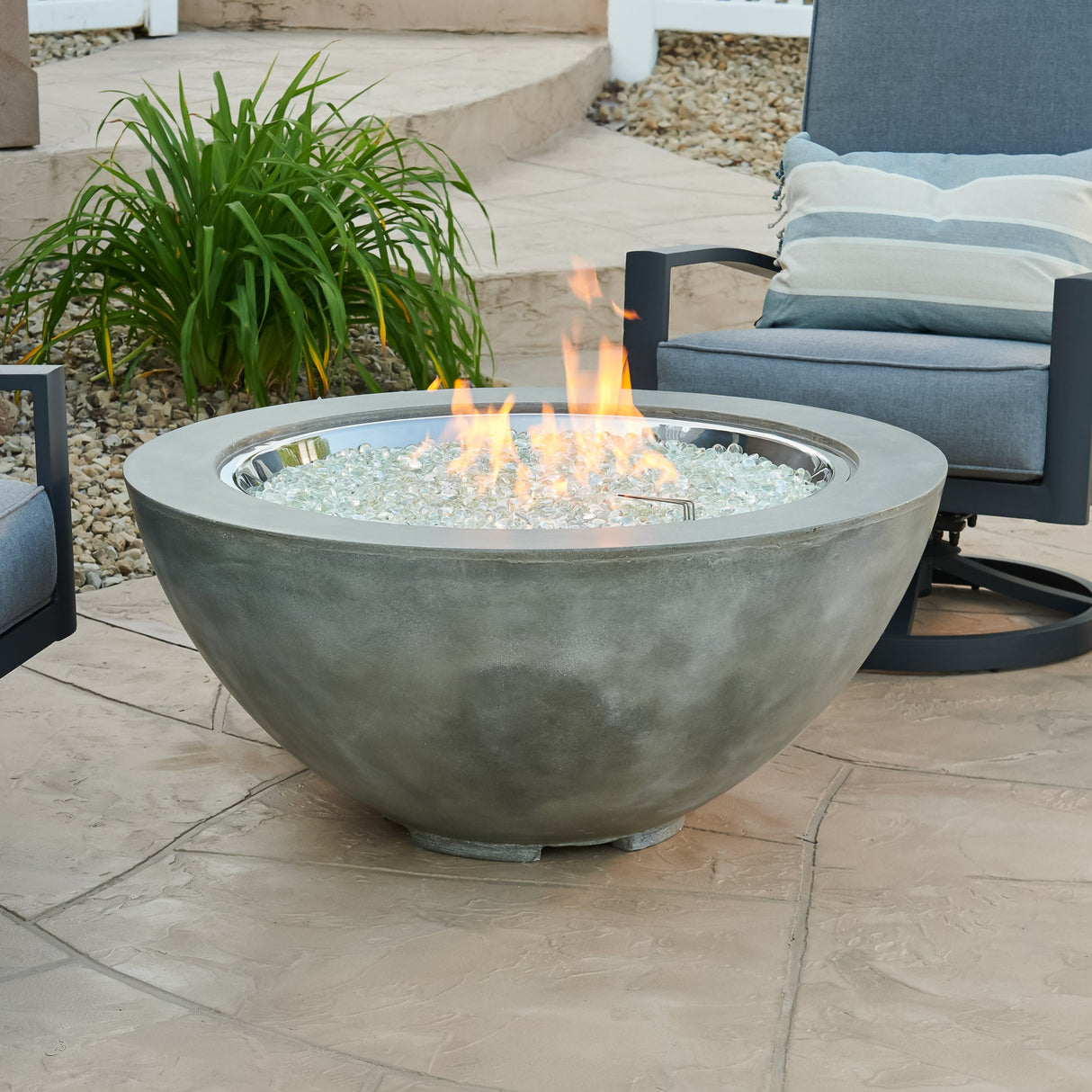 A Natural Grey Cove Round Gas Fire Pit Bowl 42" with a large flame coming from the burner