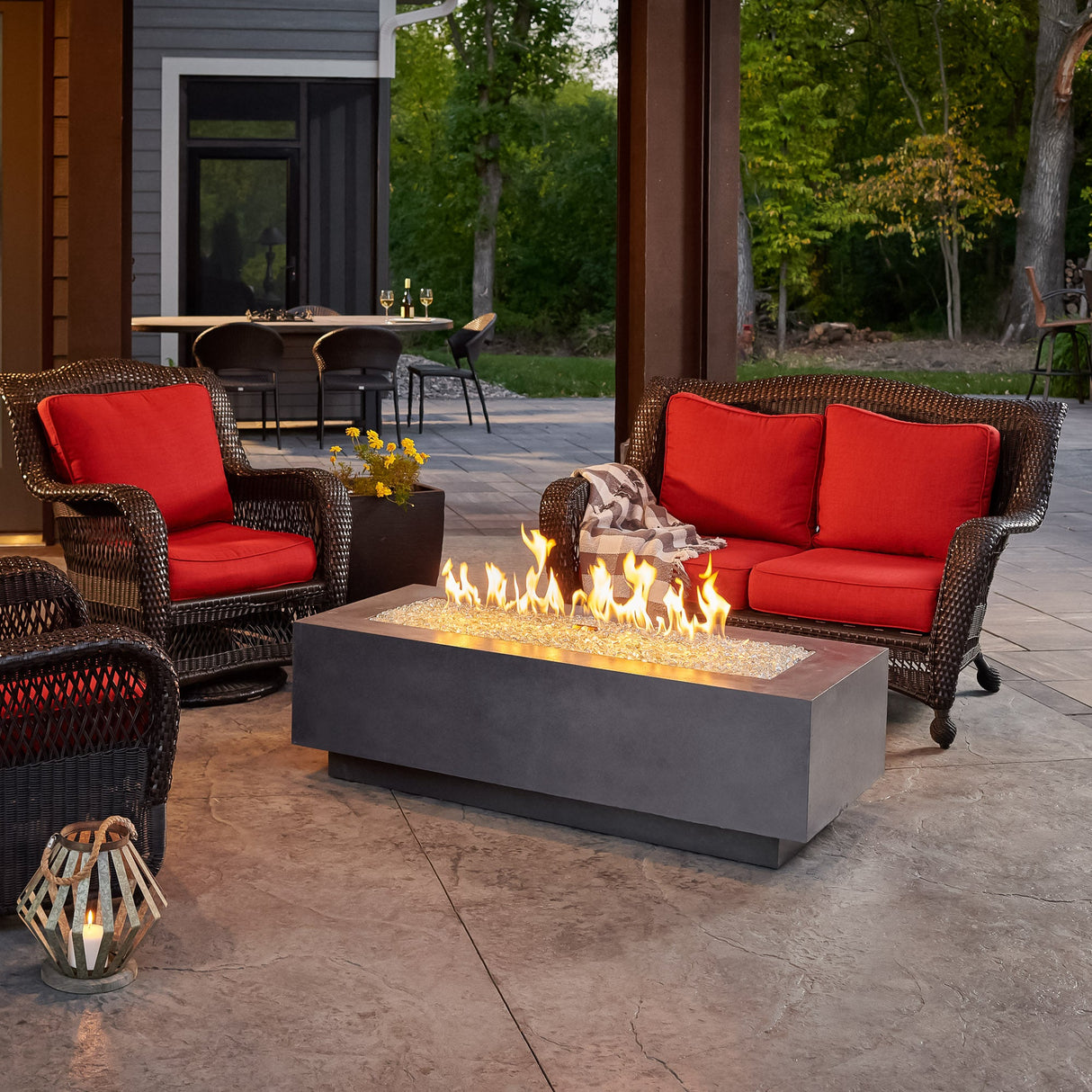 A Midnight Mist Cove Linear Gas Fire Pit Table 54" in an outdoor setting surrounded by patio furniture