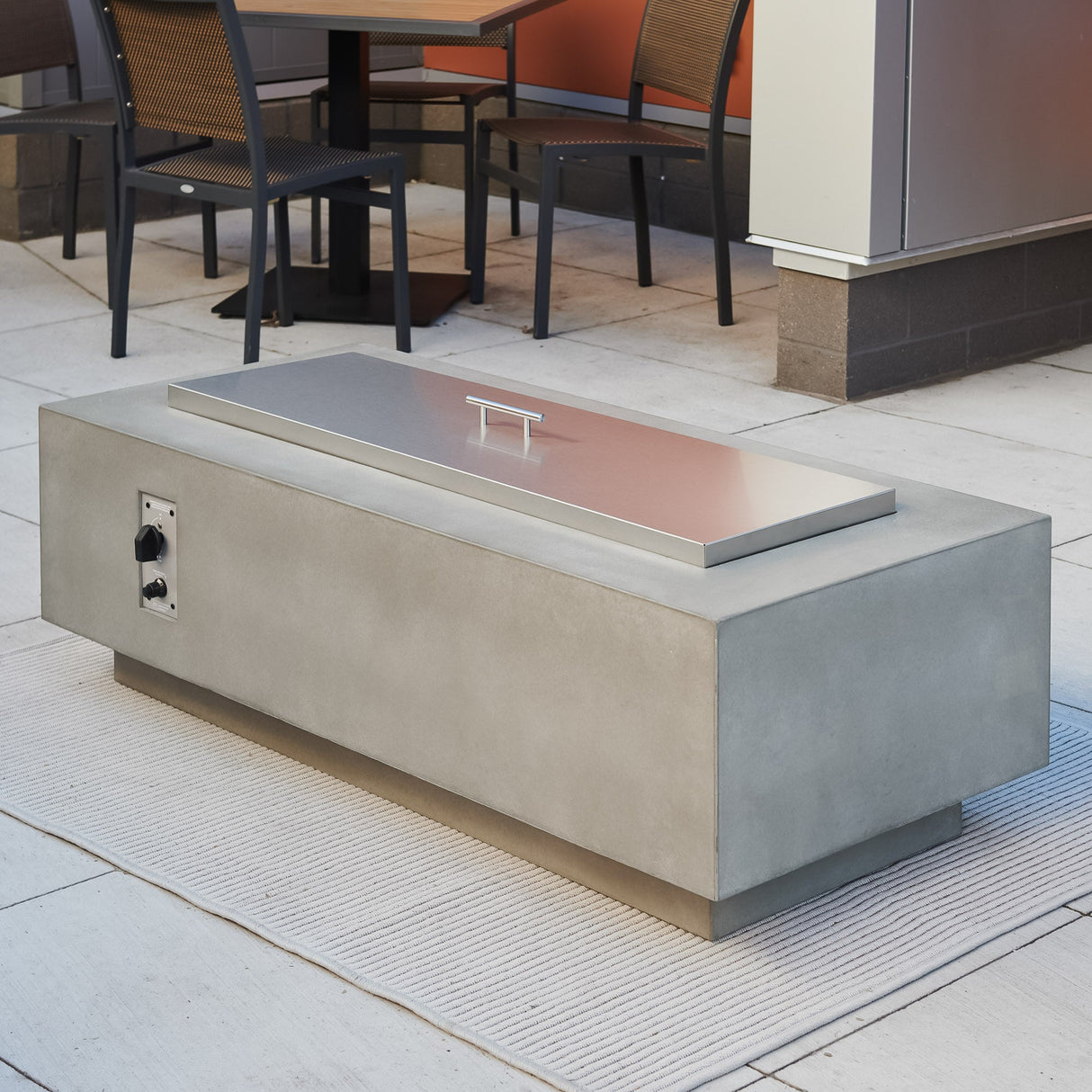 A Stainless Steel Burner Cover placed on top of the Natural Grey Cove Linear Gas Fire Pit Table 54"