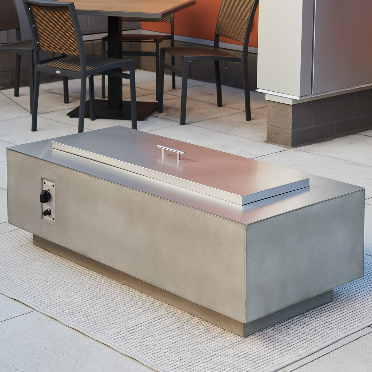 A Stainless Steel Overlay and Stainless Steel Burner Cover placed on a Natural Grey Cove Linear Gas Fire Pit Table 54"