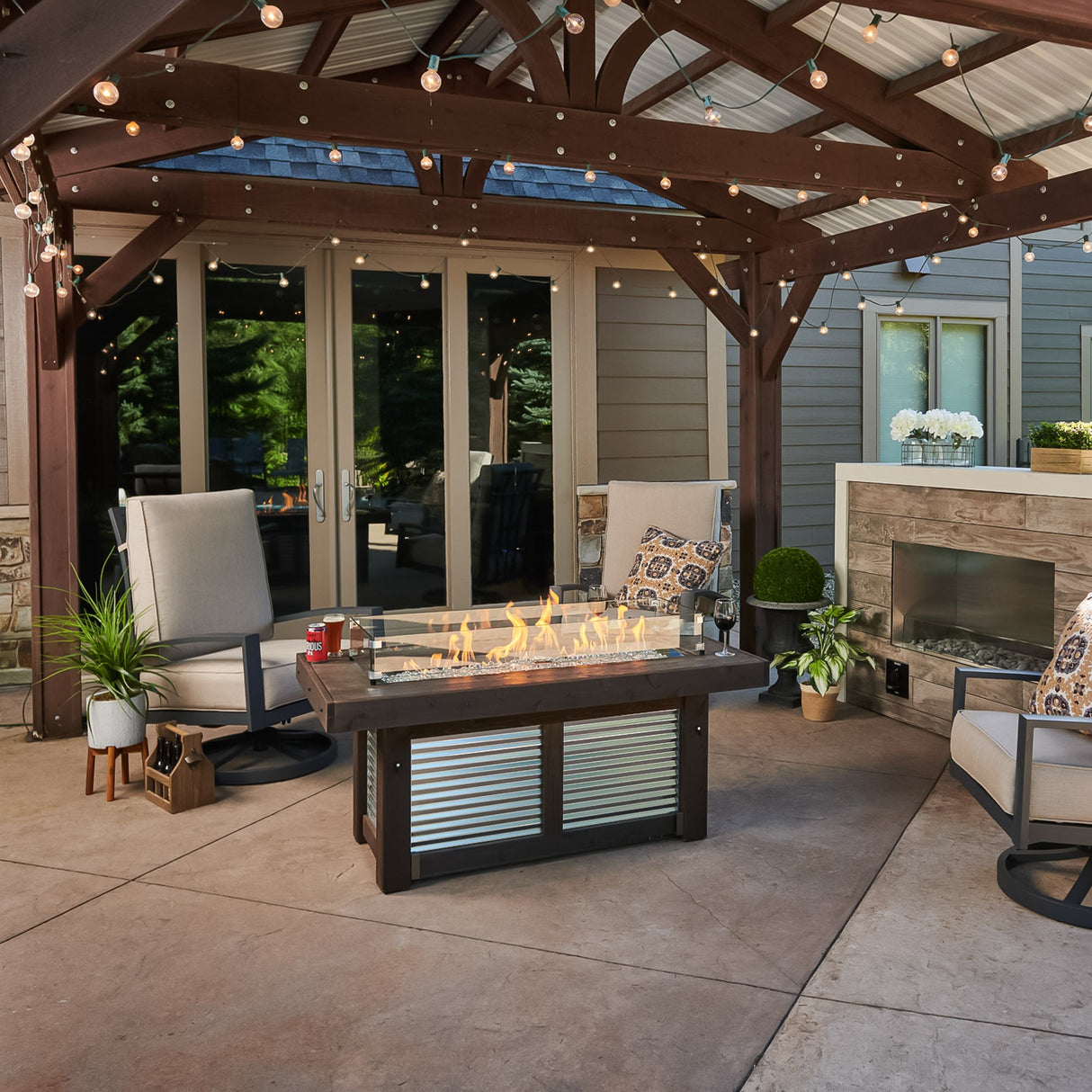 Denali Brew Linear Gas Fire Pit Table placed under a pergola setting with outdoor furniture