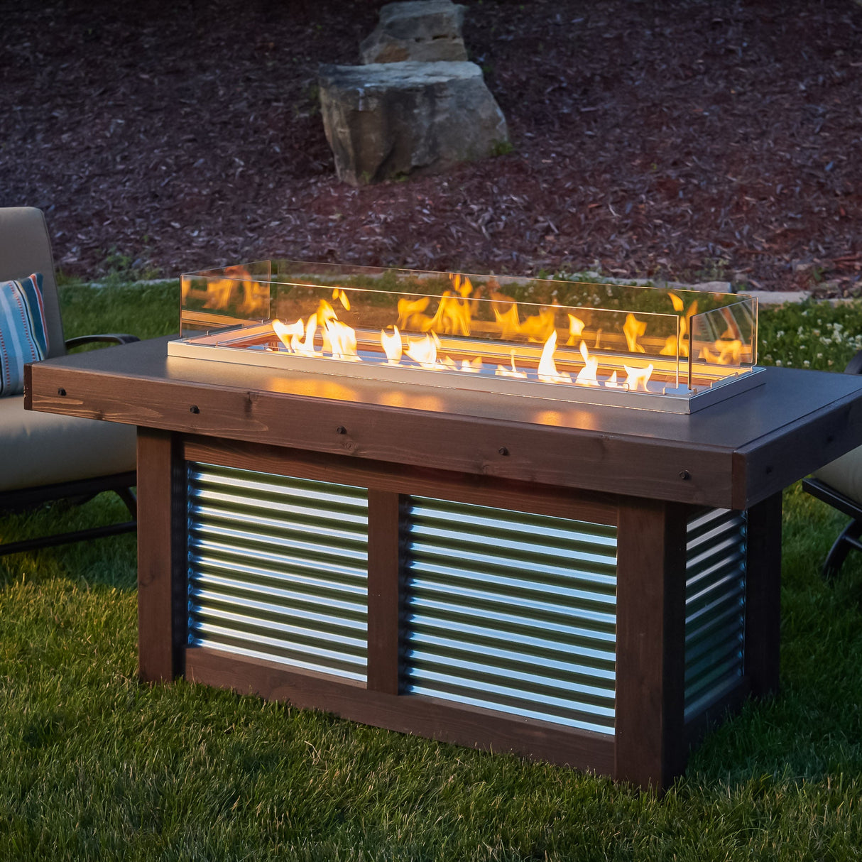 A folding glass wind guard on the Denali Brew Linear Gas Fire Pit Table