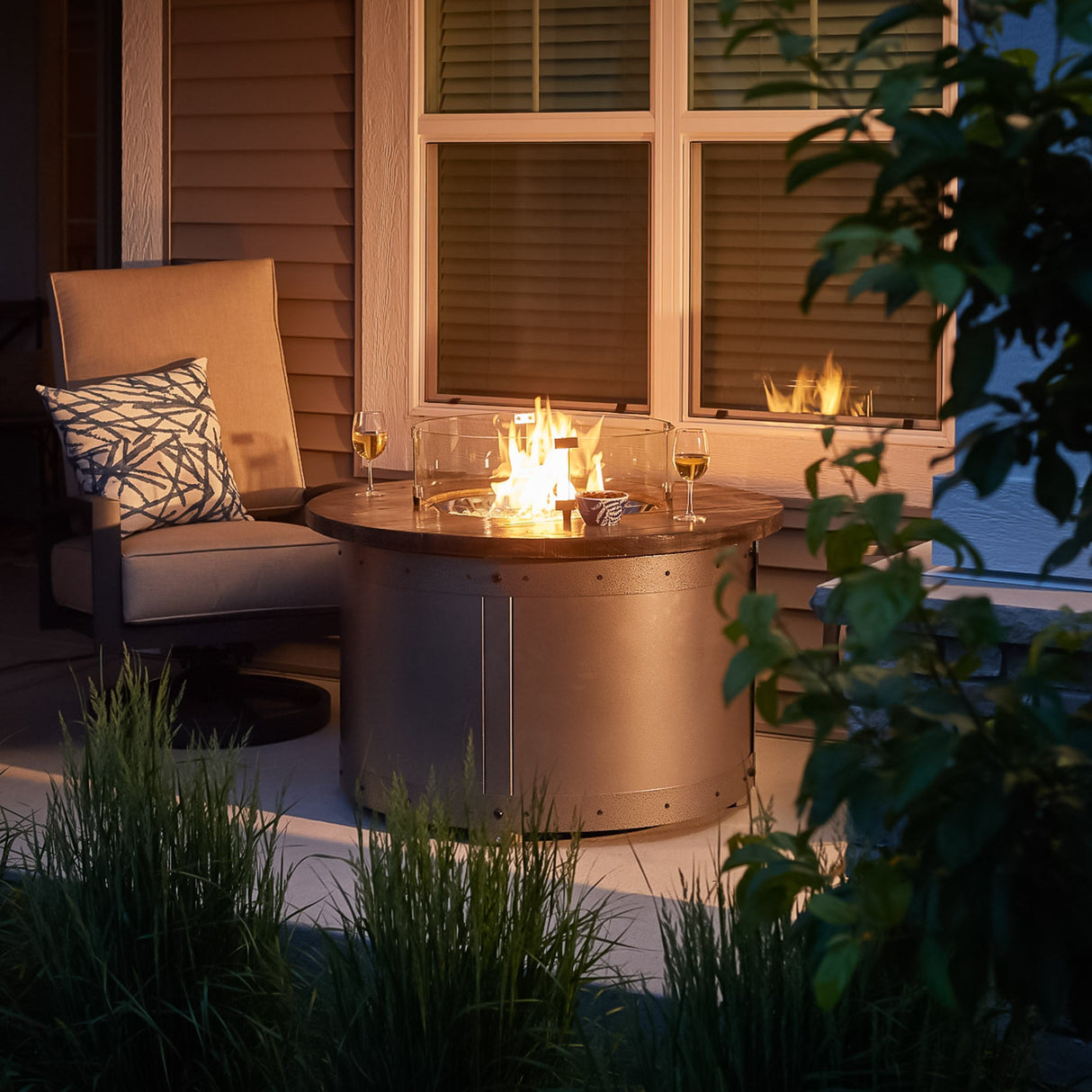 The Edison Round Gas Fire Pit Table being used as a table with food and drink around the outside
