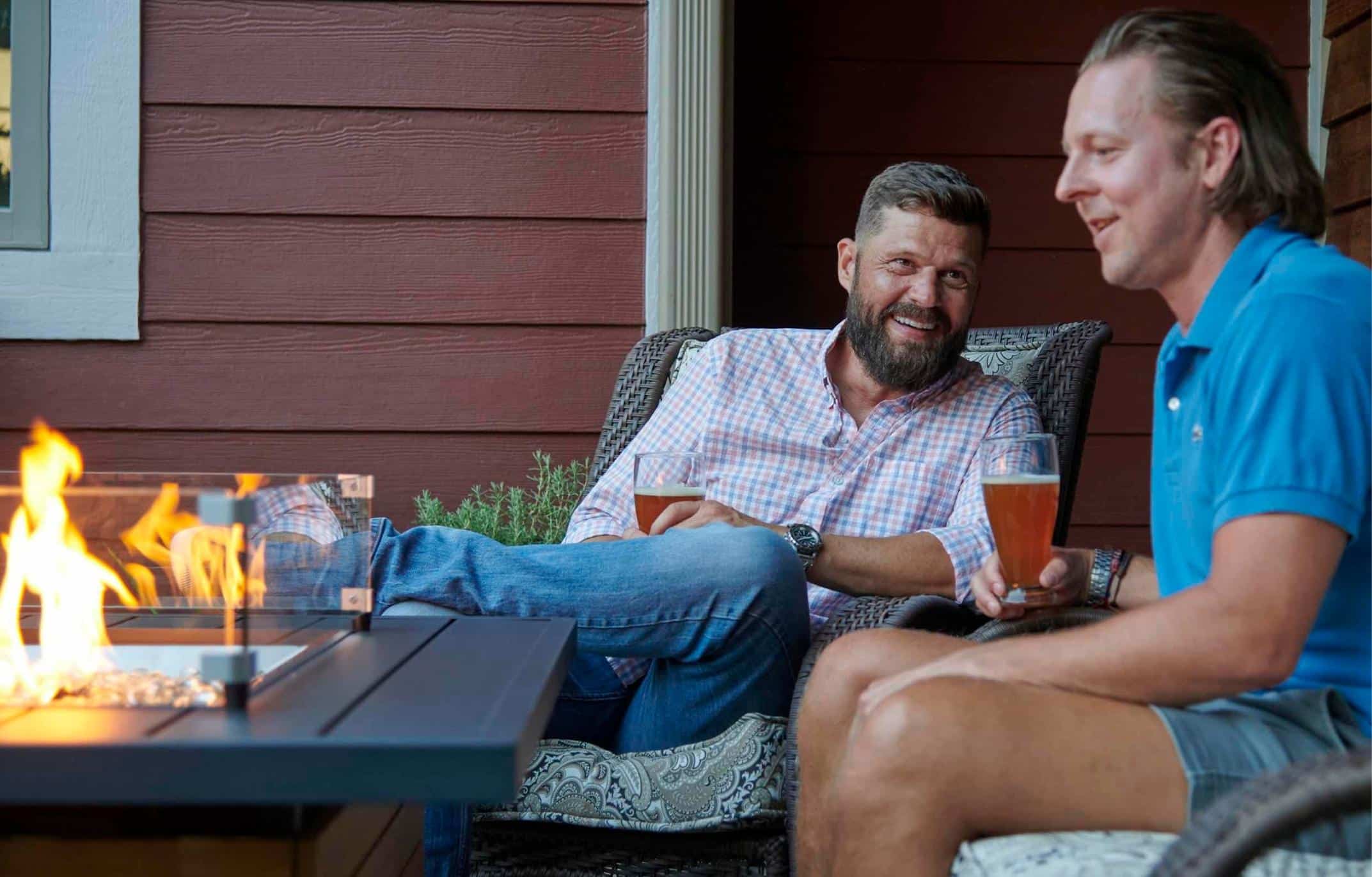 Two individuals enjoying a drink around the Darien Rectangular Gas Fire Pit Table