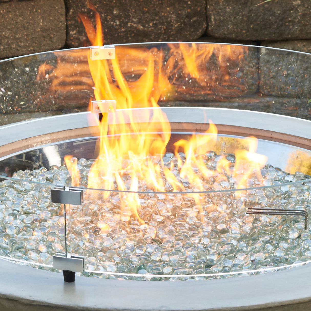 Close up of the The Round Glass Wind Guard protecting a large flame on a patio