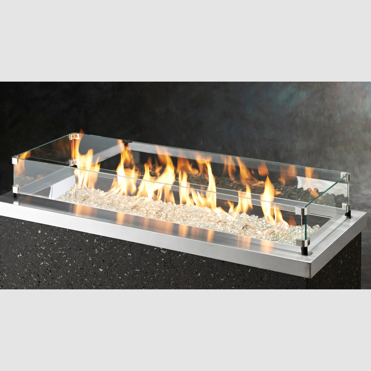 The Linear Glass Wind Guard protecting the flame of a fire pit table in a studio