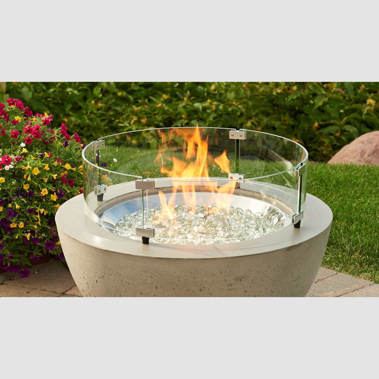 The Round Glass Wind Guard used to protect a flame from the fire pit bowl in a patio setting