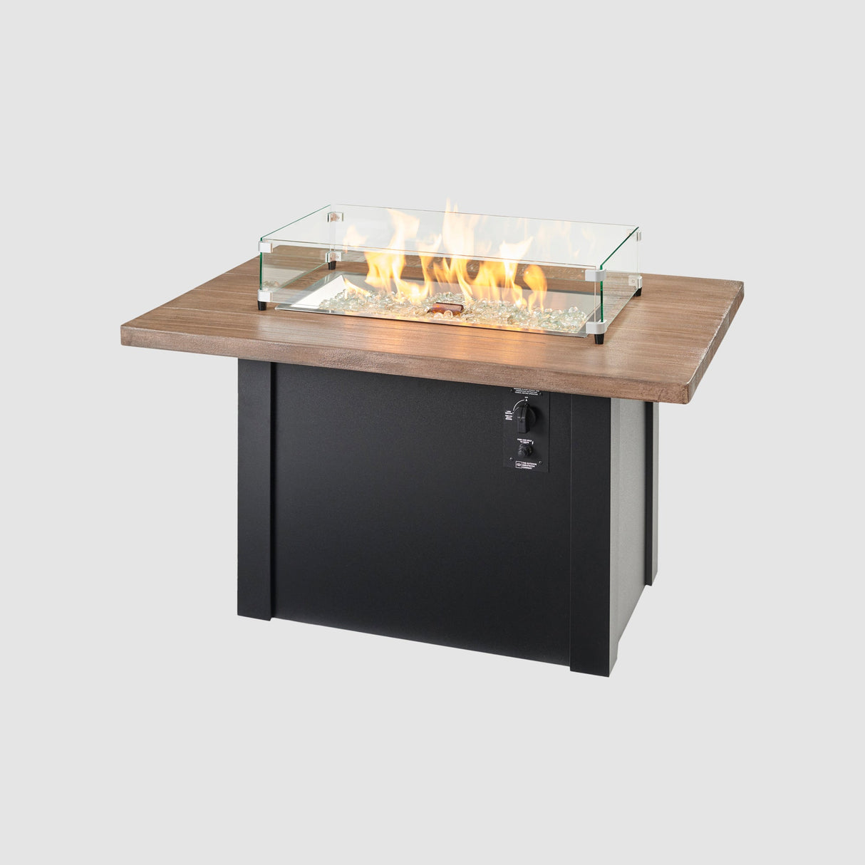 A glass wind guard on top of a Havenwood Rectangular Gas Fire Pit Table with a Driftwood top and Luverne Black base