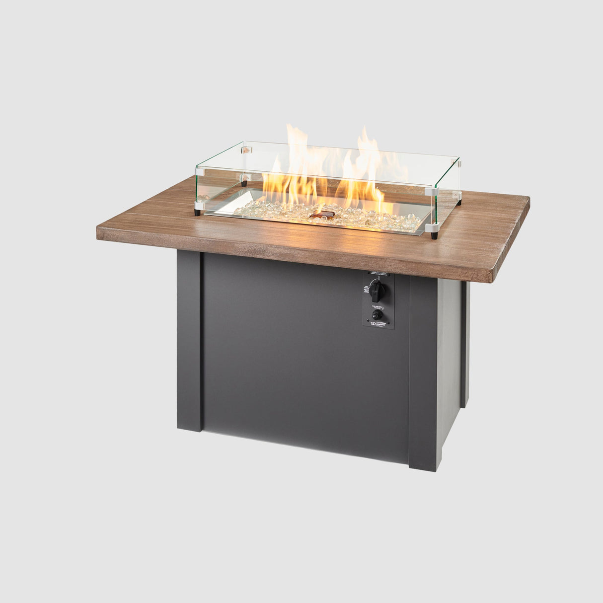 A glass wind guard placed on top of a Havenwood Rectangular Gas Fire Pit Table with a Driftwood top and Graphite Grey base