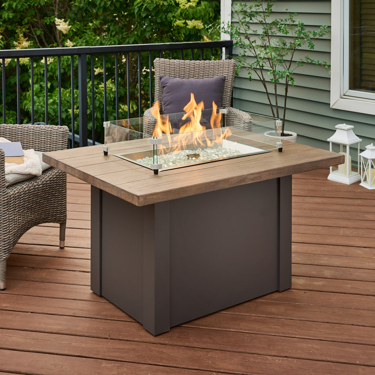 A Havenwood Rectangular Gas Fire Pit Table with a glass wind guard on a spacious outdoor space
