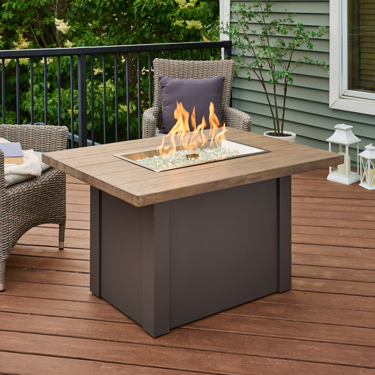 A large flame coming from the burner of a Havenwood Rectangular Gas Fire Pit Table with a Driftwood top and Graphite Grey base