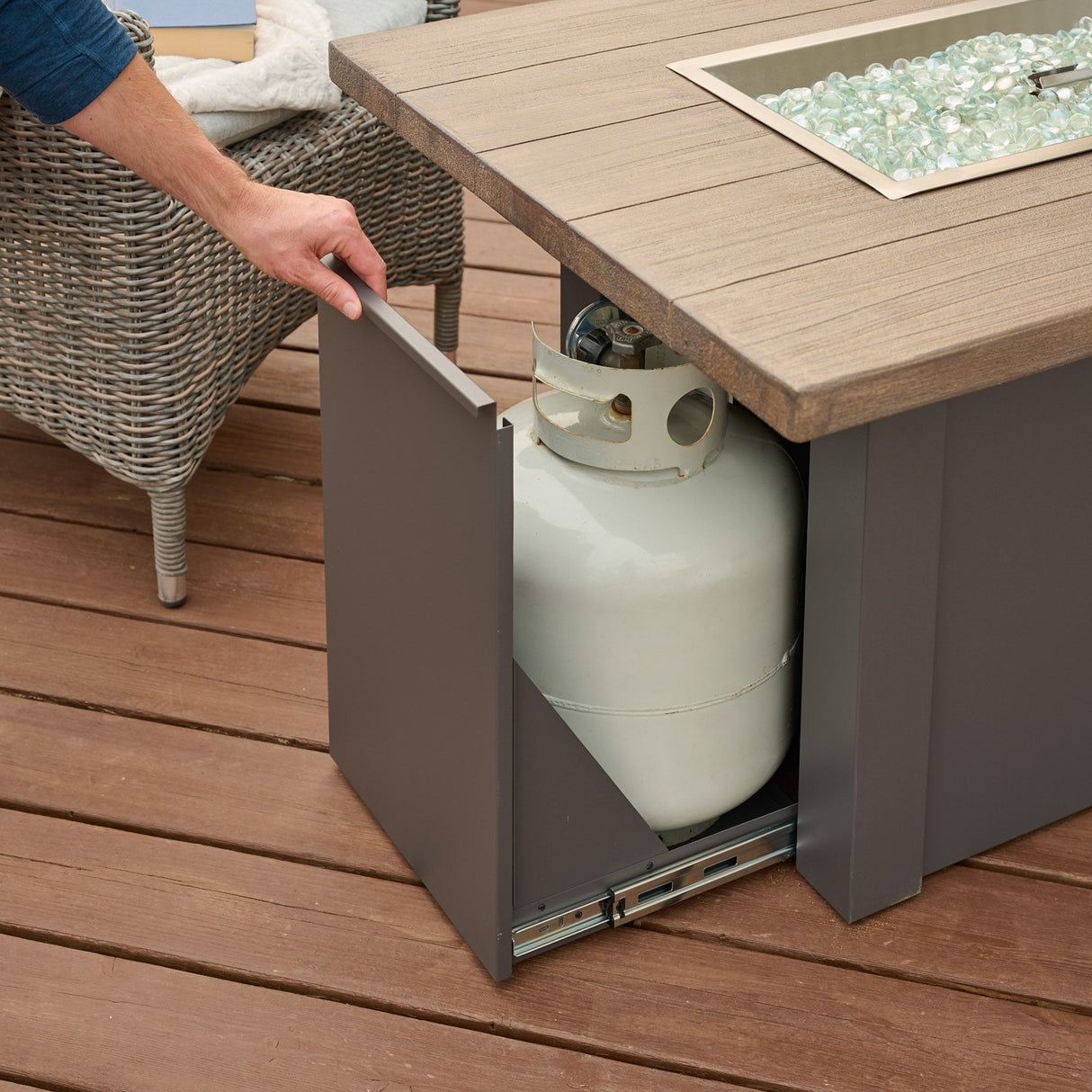 An individual opening the side access door of a Havenwood Rectangular Gas Fire Pit Table
