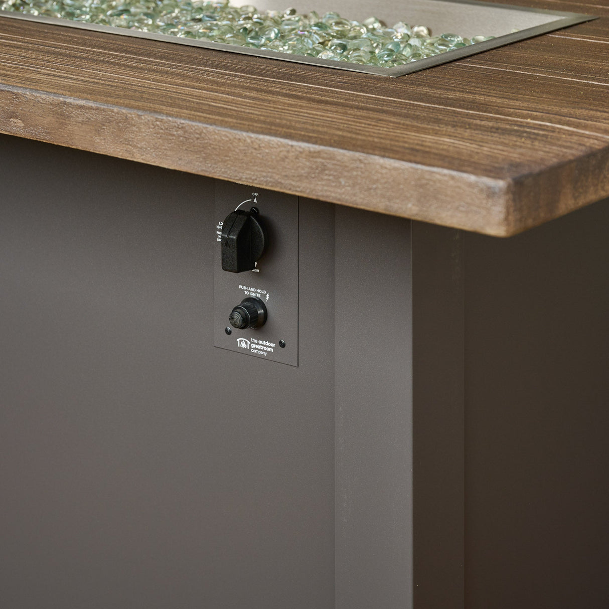 A close up view of the control panel used on a Havenwood Linear Gas Fire Pit Table with a Driftwood top and Graphite Grey base