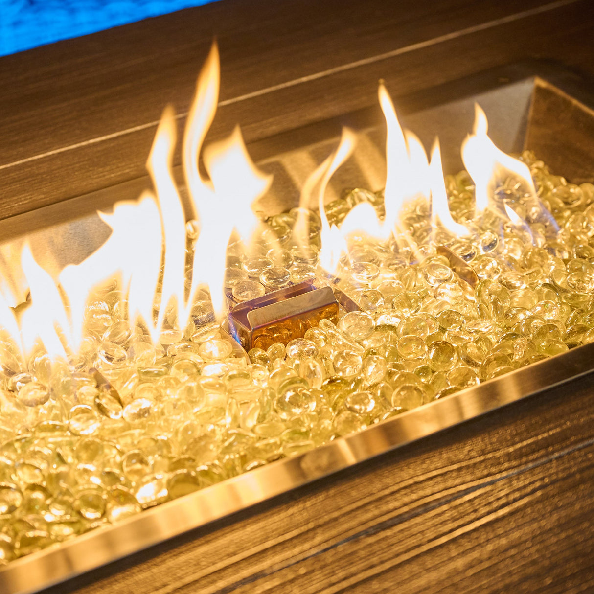 A close up of the flame coming from the burner of a Havenwood Rectangular Gas Fire Pit Table